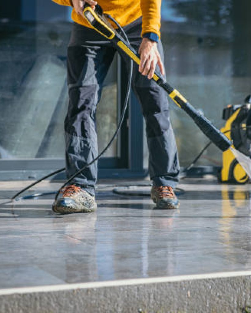 Man cleaning the terrace with high pressure cleaner on beautiful sunny day.